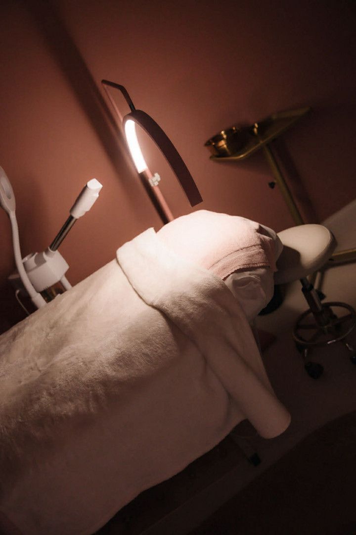 Massage table in a dim spa room with a white towel and warm lamp lighting.