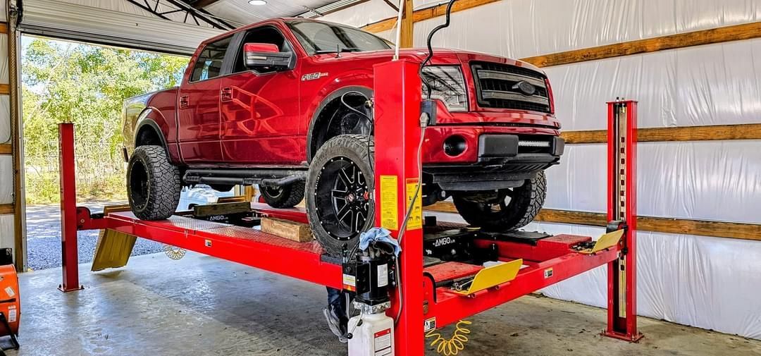 A red truck is sitting on top of a red lift in a garage.