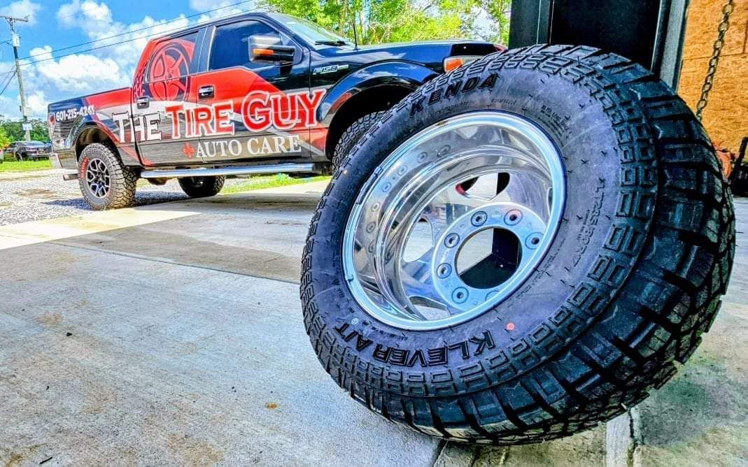 A tire is sitting on the ground next to a truck.
