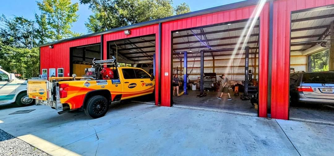 A yellow truck is parked in front of a red garage.