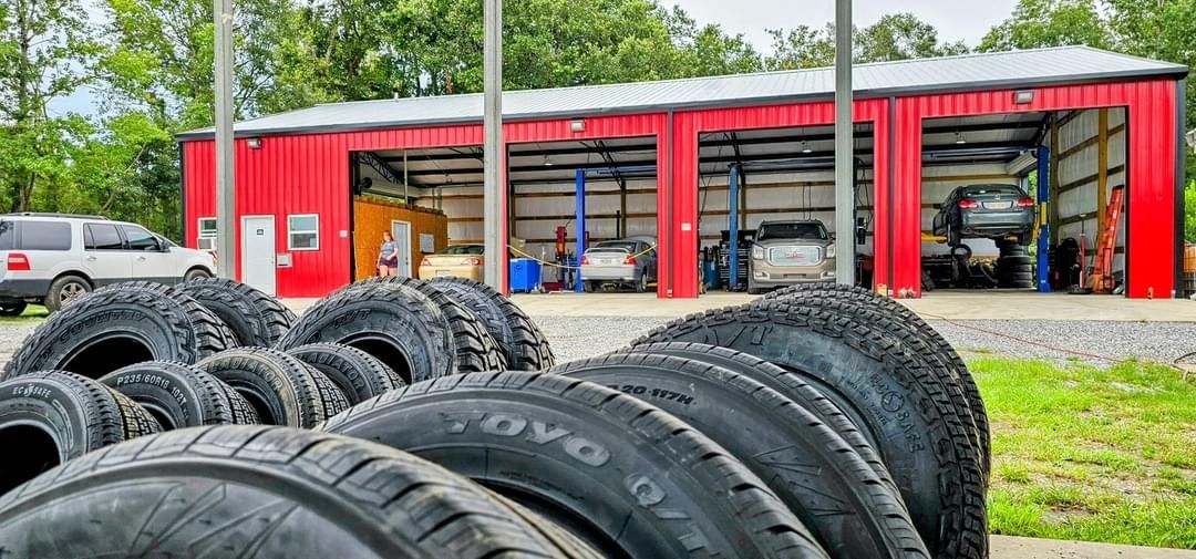 A bunch of tires are stacked in front of a garage.
