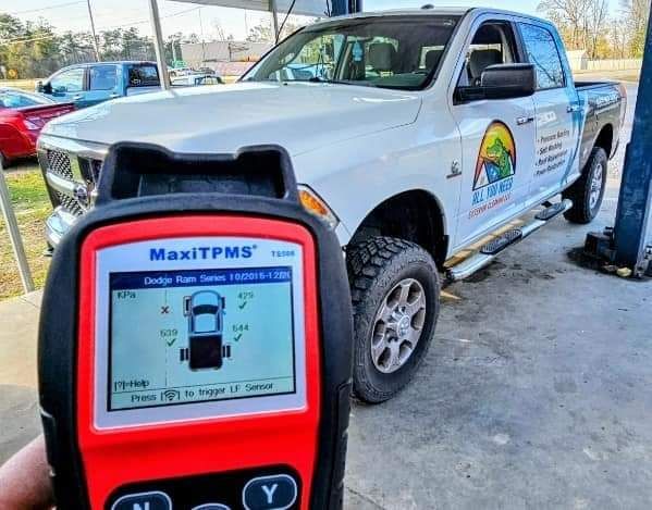 A person is holding a tpms device in front of a truck.