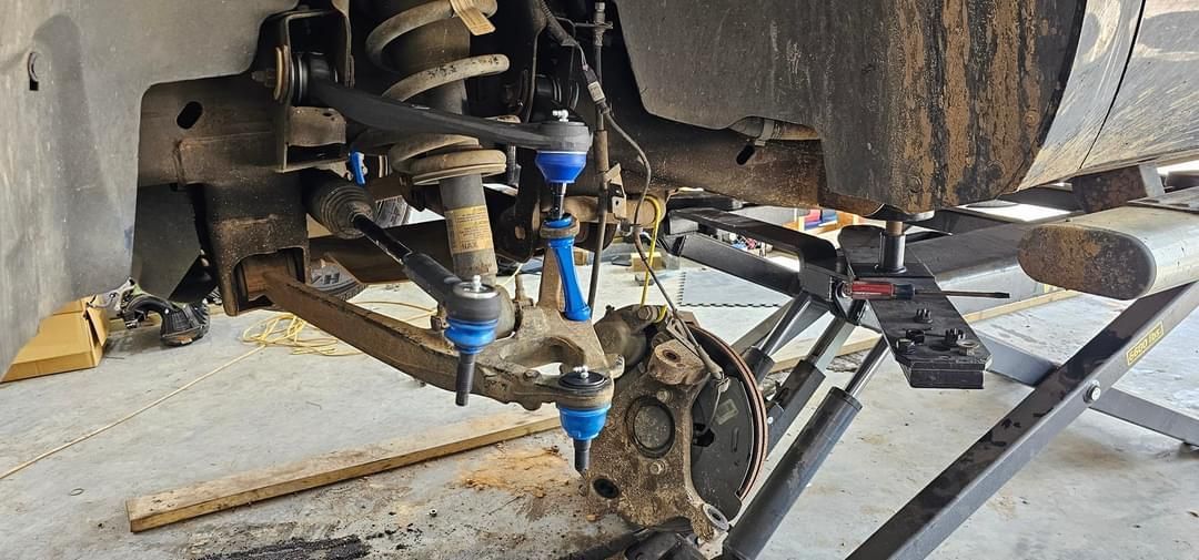 A car is being repaired in a garage with a jack.