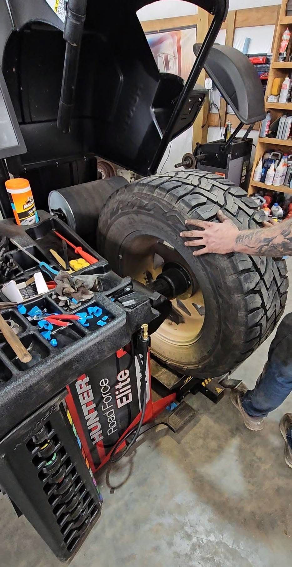A stack of tires and a tire changer in a garage.
