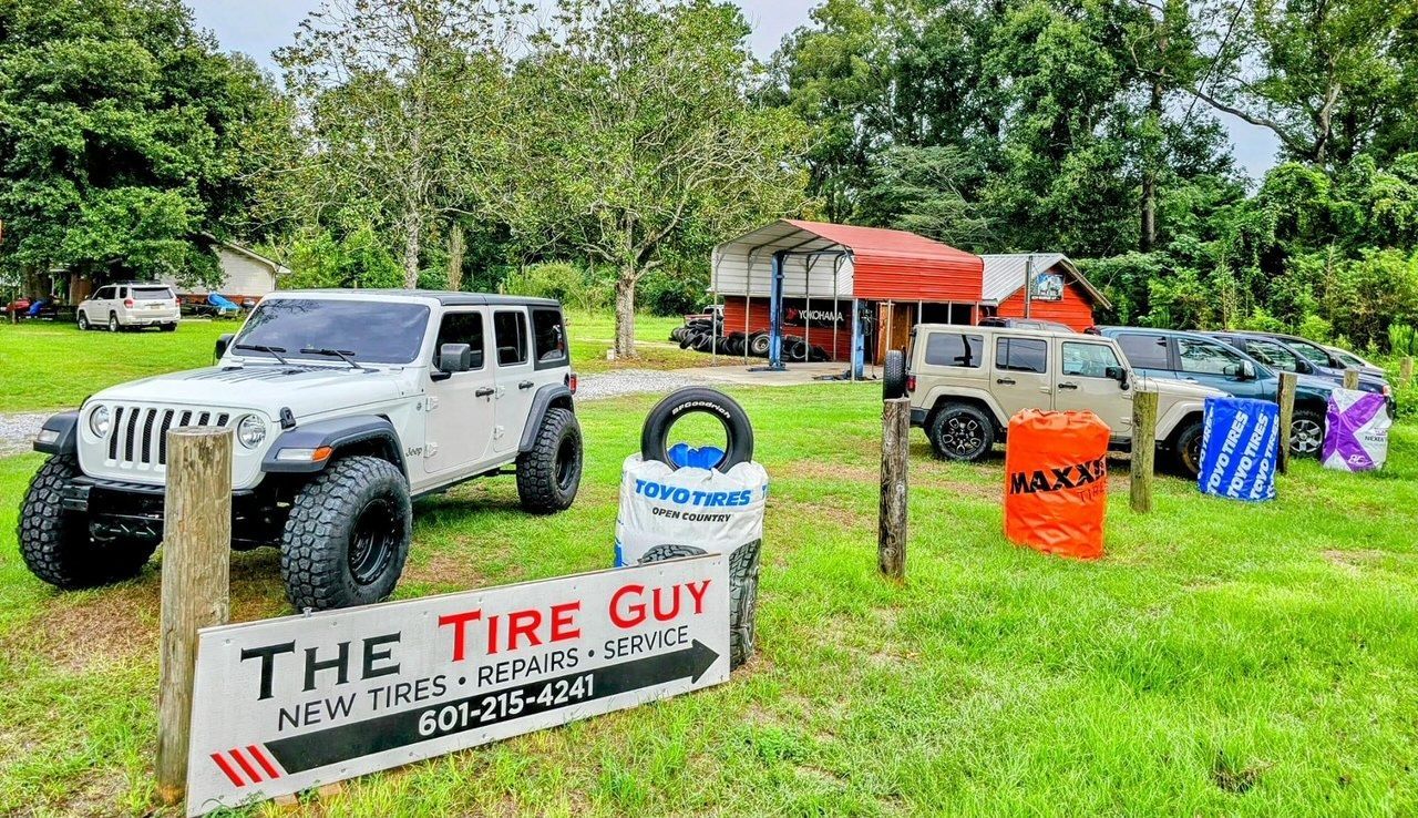 A white jeep is parked in front of a tire shop.