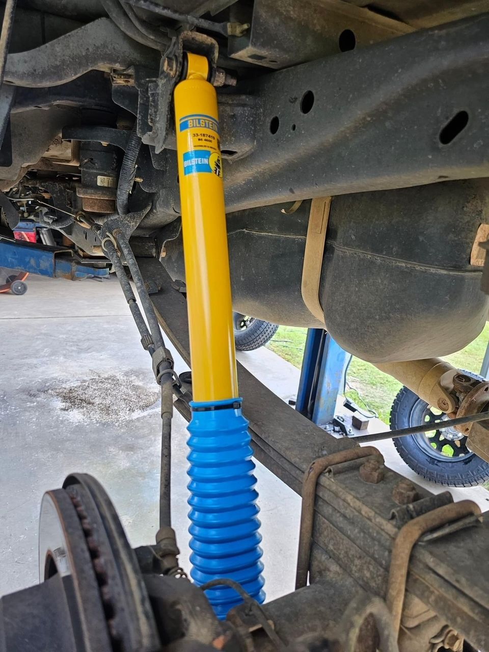 A yellow and blue shock absorber is attached to the underside of a truck.