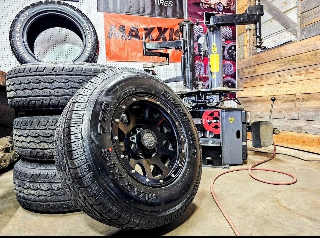 A stack of tires and a tire changer in a garage.