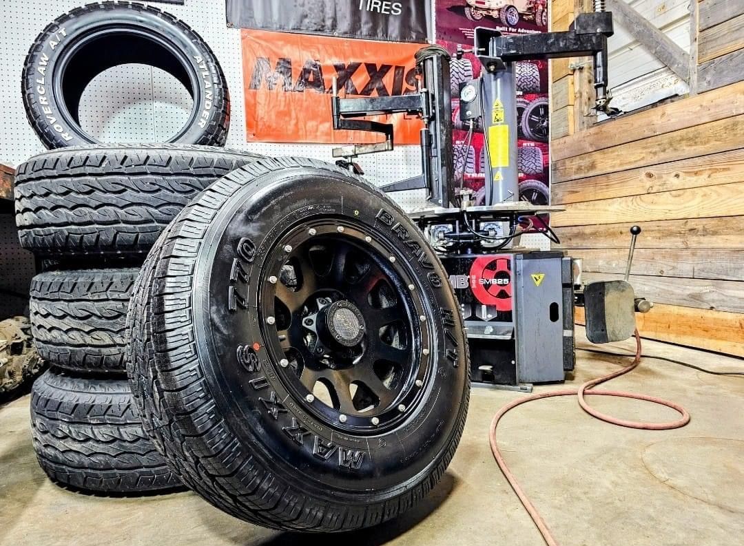 A stack of tires and a tire changer in a garage.