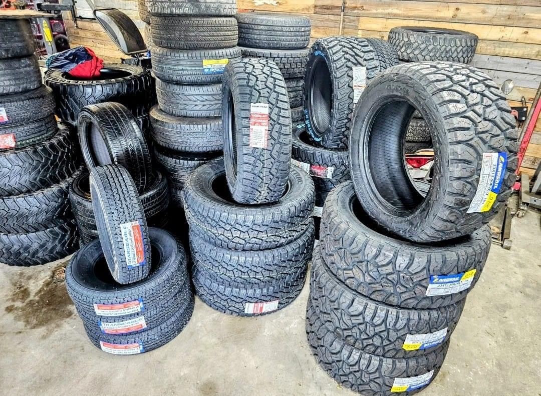 A bunch of tires are stacked on top of each other in a garage.