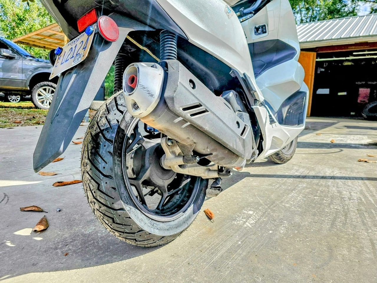 A scooter is parked in a driveway in front of a garage