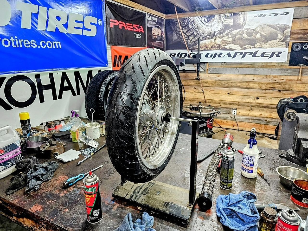 A motorcycle tire is sitting on top of a table in a garage.