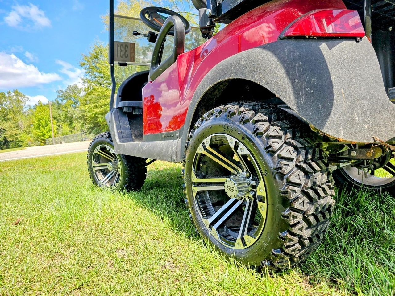 A red golf cart is parked on a lush green field.
