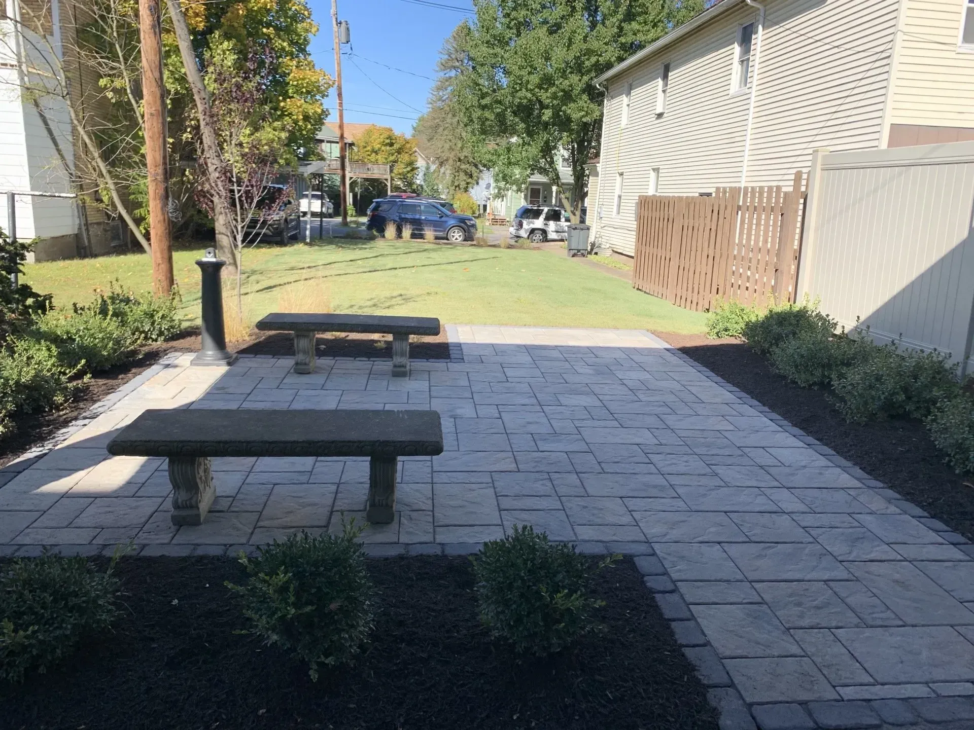 A patio with a bench and a table in front of a house.