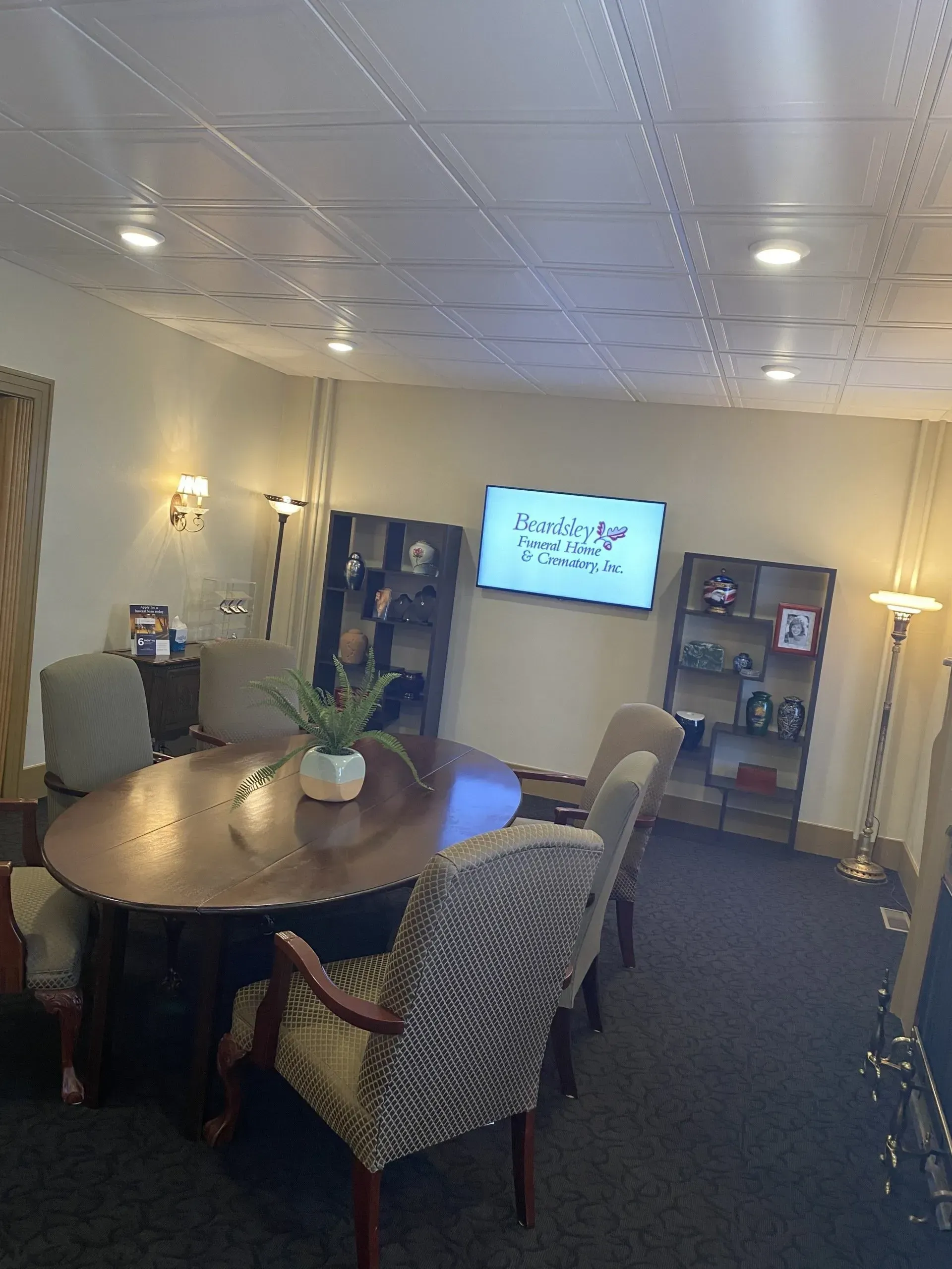 A conference room with a table and chairs and a flat screen tv on the wall.