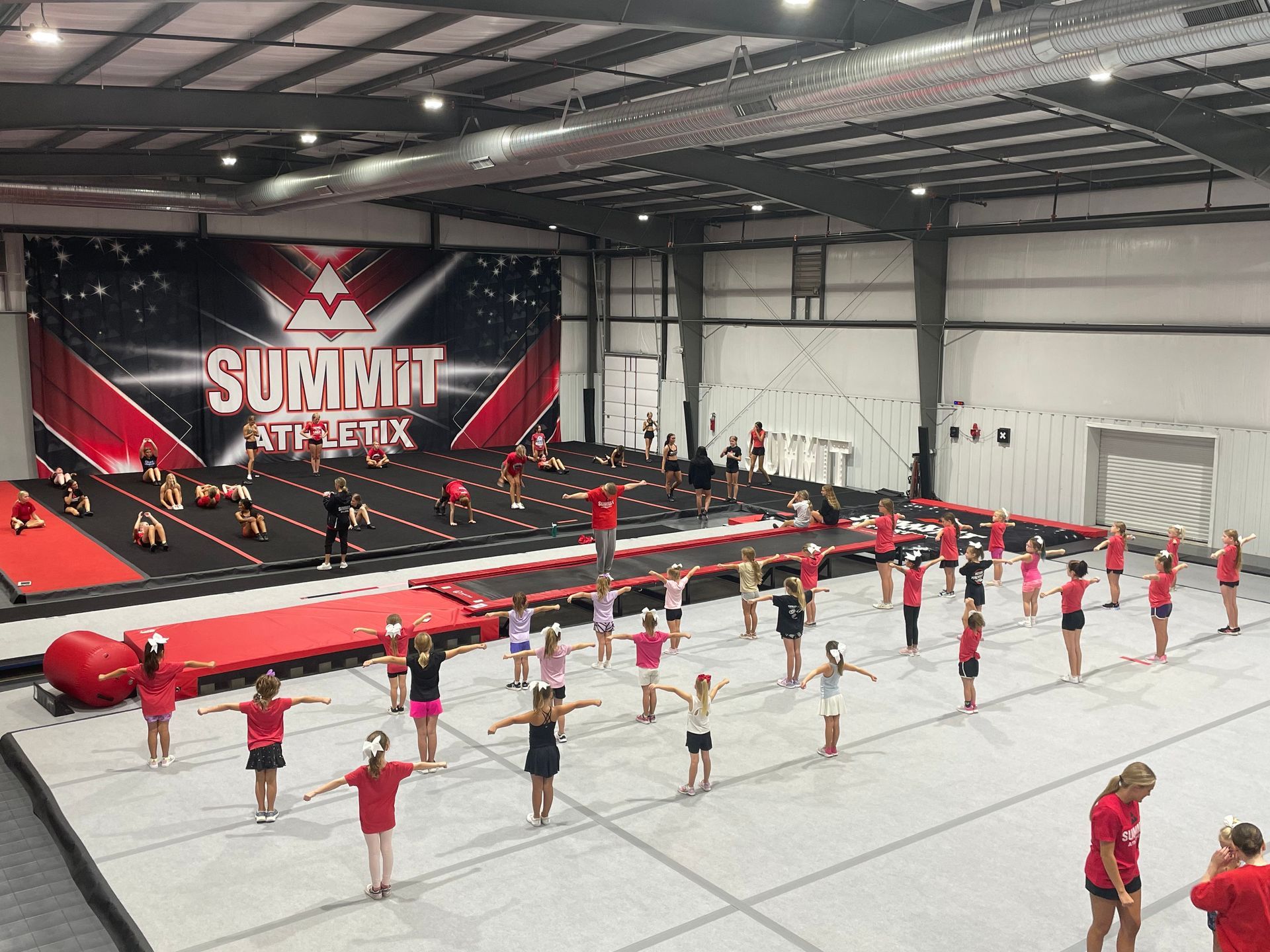 A group of children are practicing gymnastics in a gym.