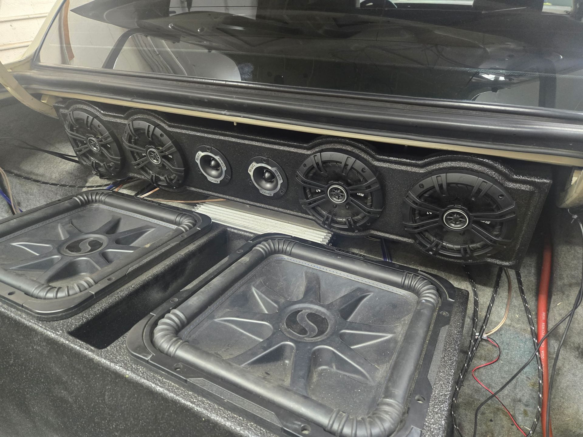 Car audio setup with speakers in the trunk. Black finish, multiple speakers, two large subwoofers.