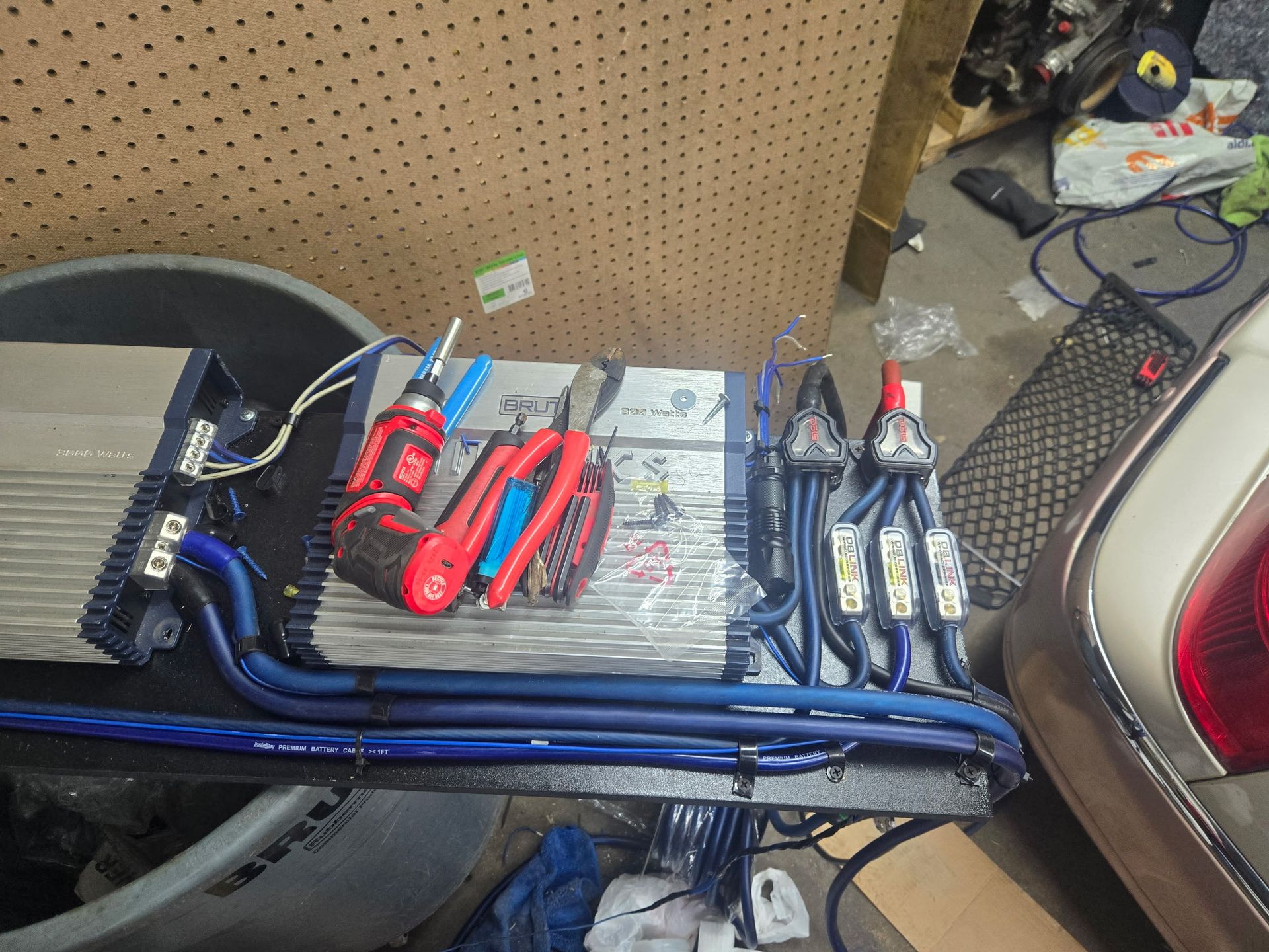 Car audio amplifier setup with tools, wires, and connections.