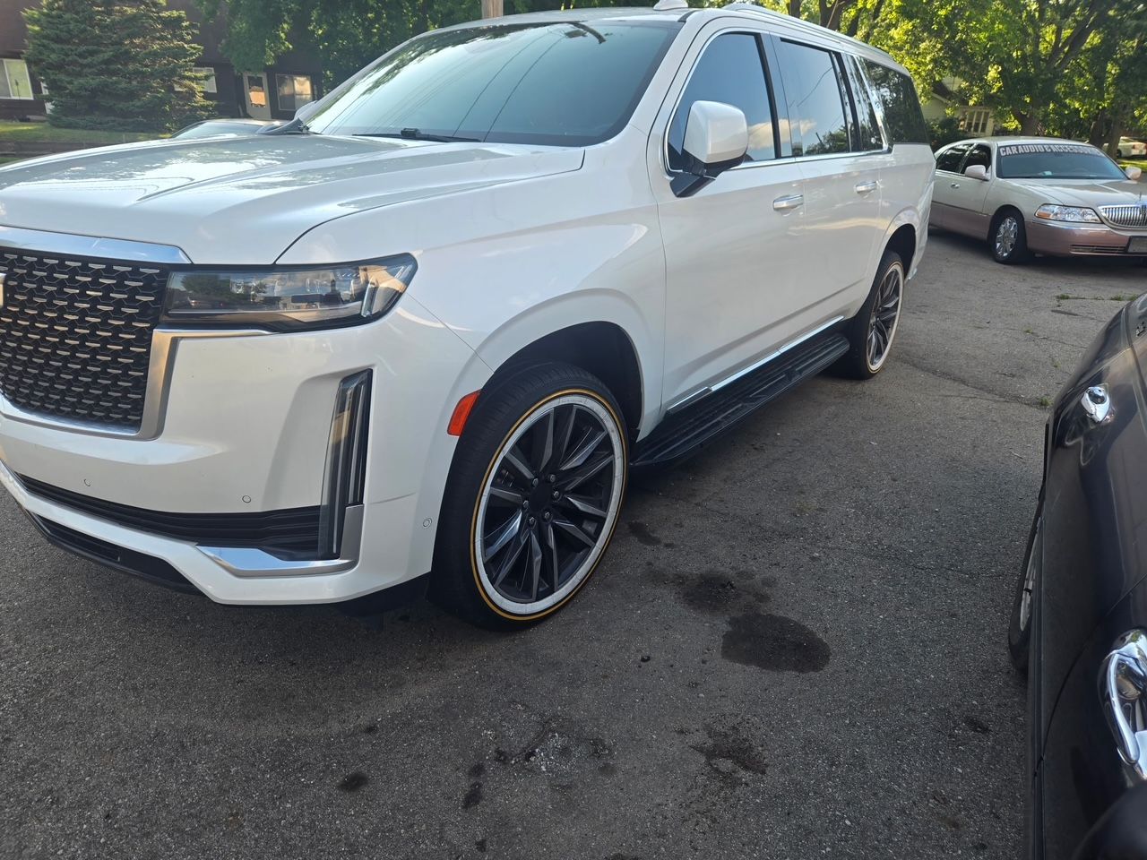 White Cadillac SUV with black and chrome rims parked on asphalt.