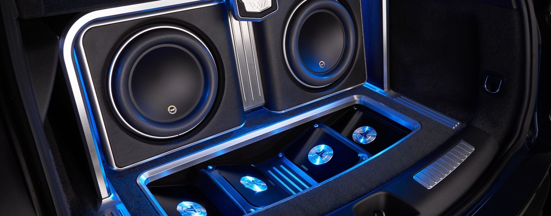 Car audio system with subwoofers and blue lighting.