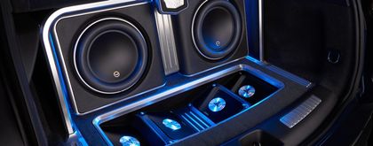 Car audio system with subwoofers and blue lighting.