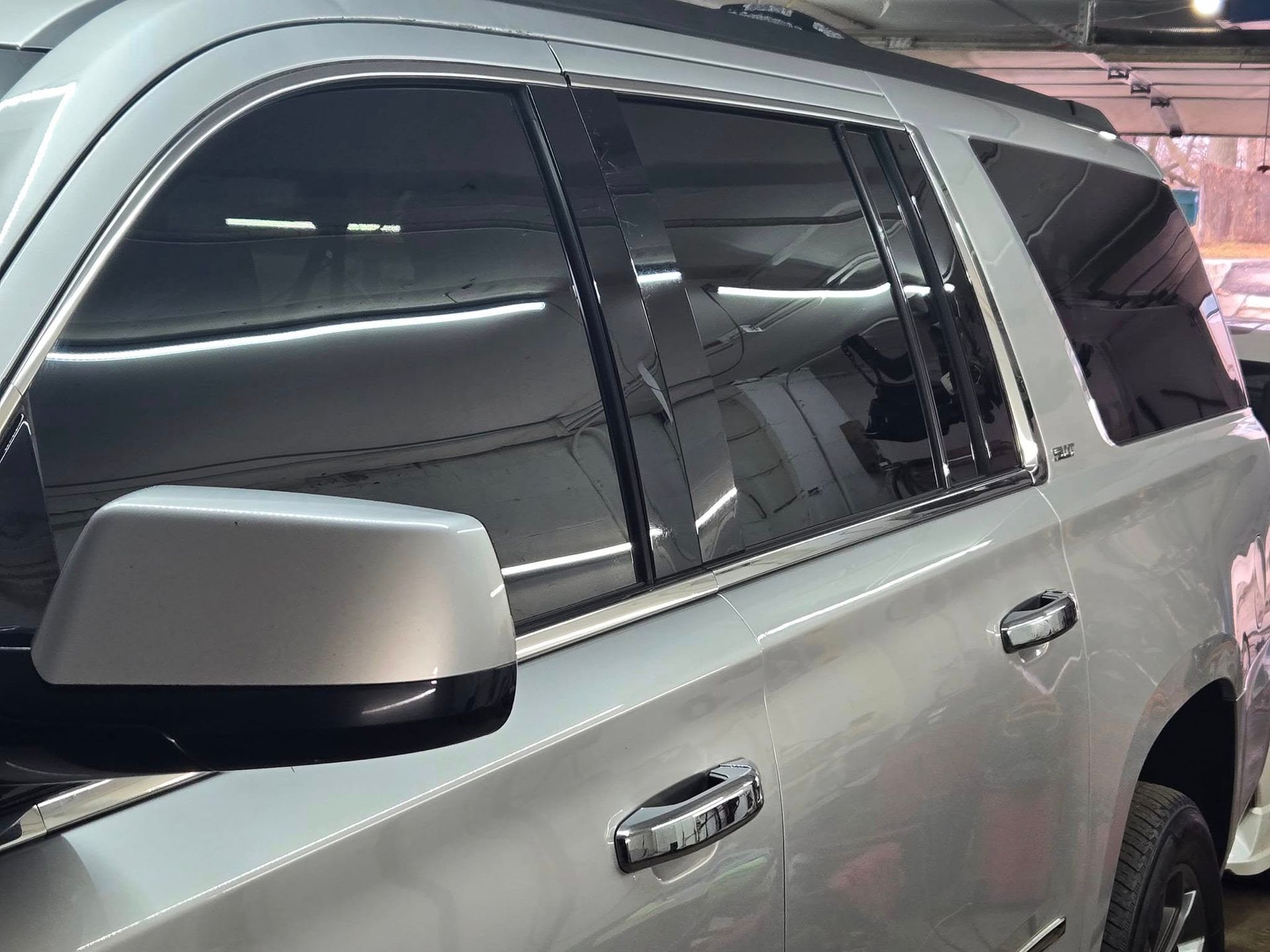 Silver SUV with tinted windows and side mirror, parked indoors.