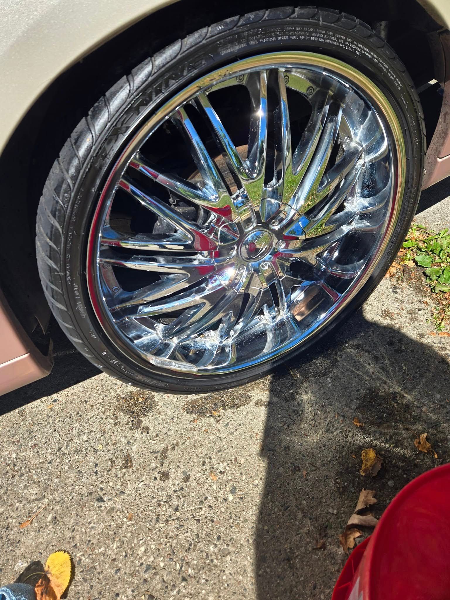 Shiny chrome car wheel on concrete surface.