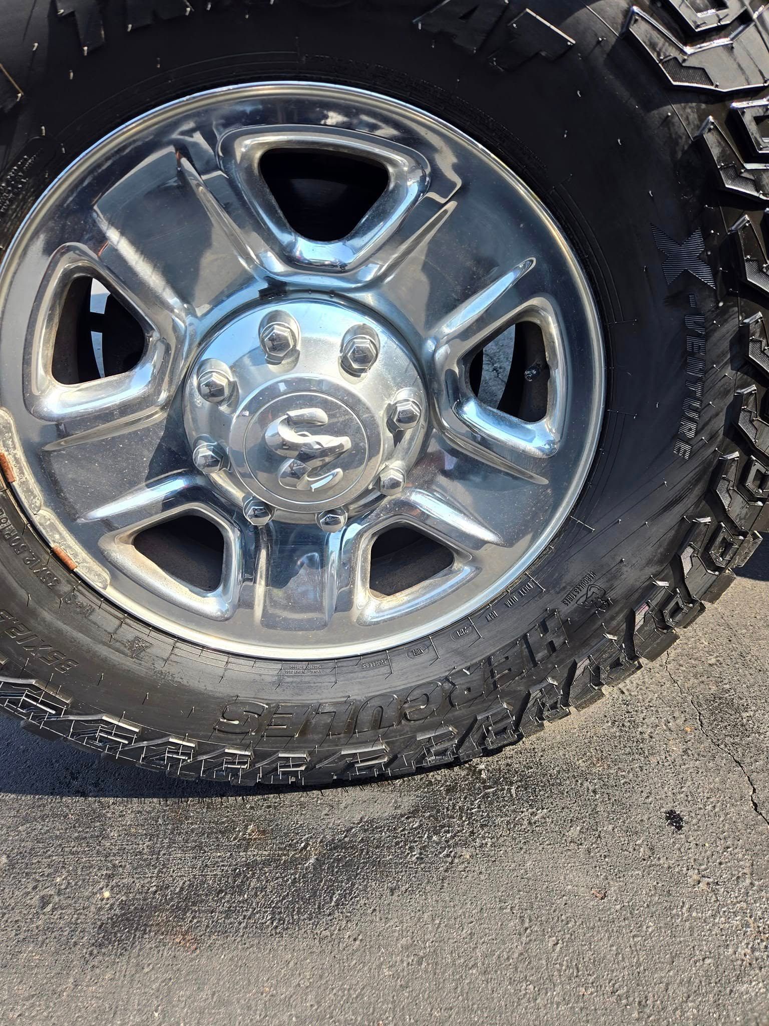 Close-up of a chrome truck wheel and tire on an asphalt surface.