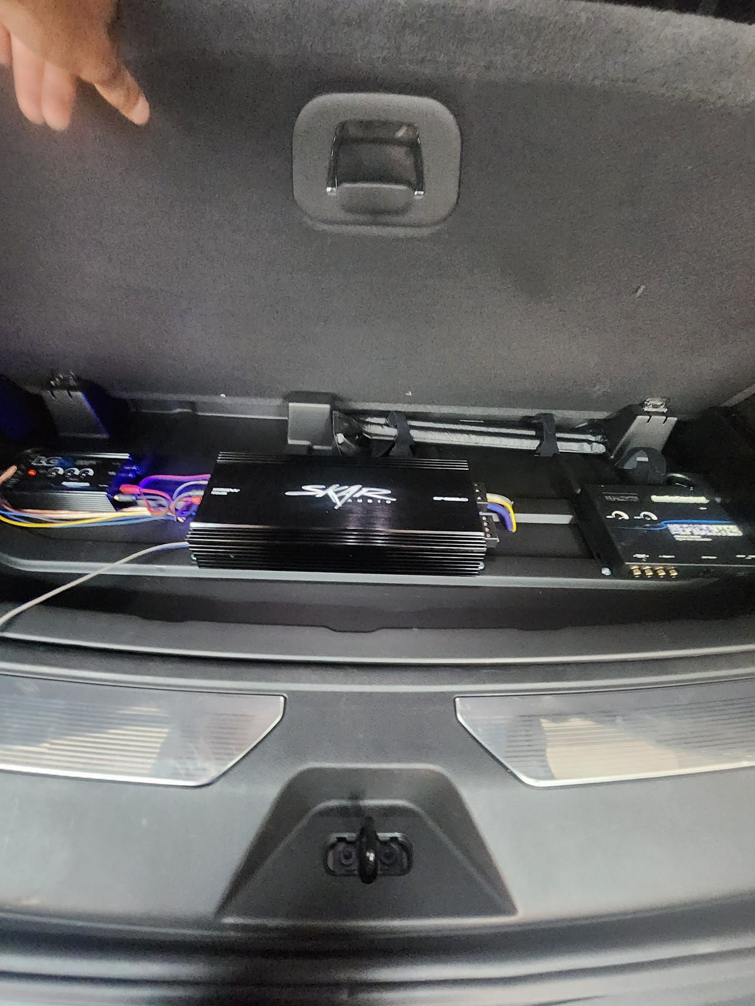 Car trunk with amplifiers and speaker equipment installed on a platform.
