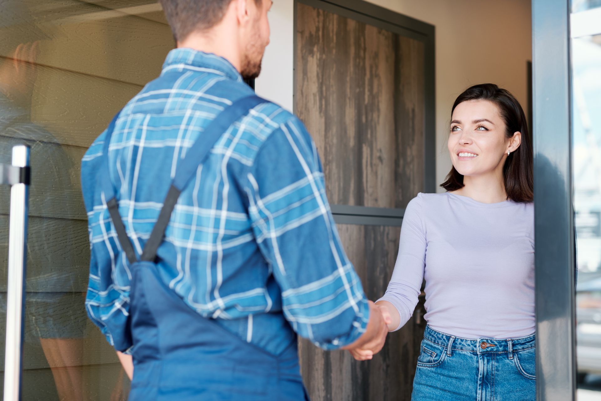A man is shaking hands with a woman in a doorway.