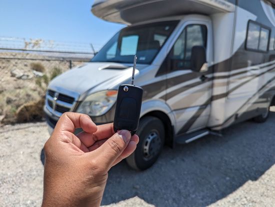 A person is holding a remote control in front of a rv.