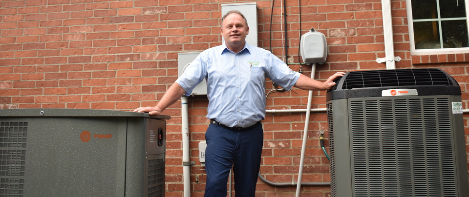 a man is standing in front of a brick wall next to an air conditioner .