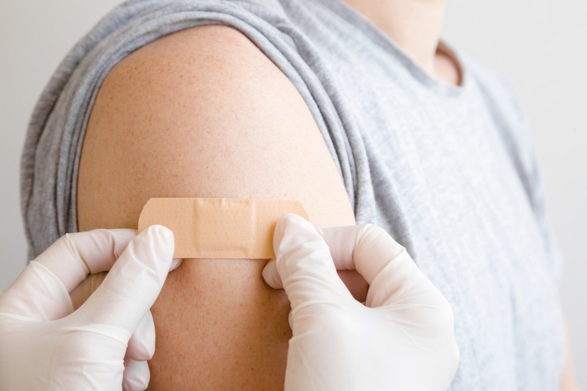 doctor applying bandage over vaccination site on skin