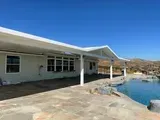 A light-colored house with a patio, pool, and clear blue sky.
