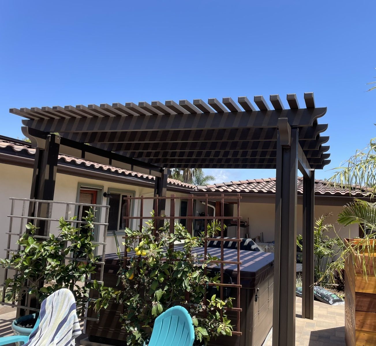 Wooden pergola over a hot tub in a backyard with blue sky.