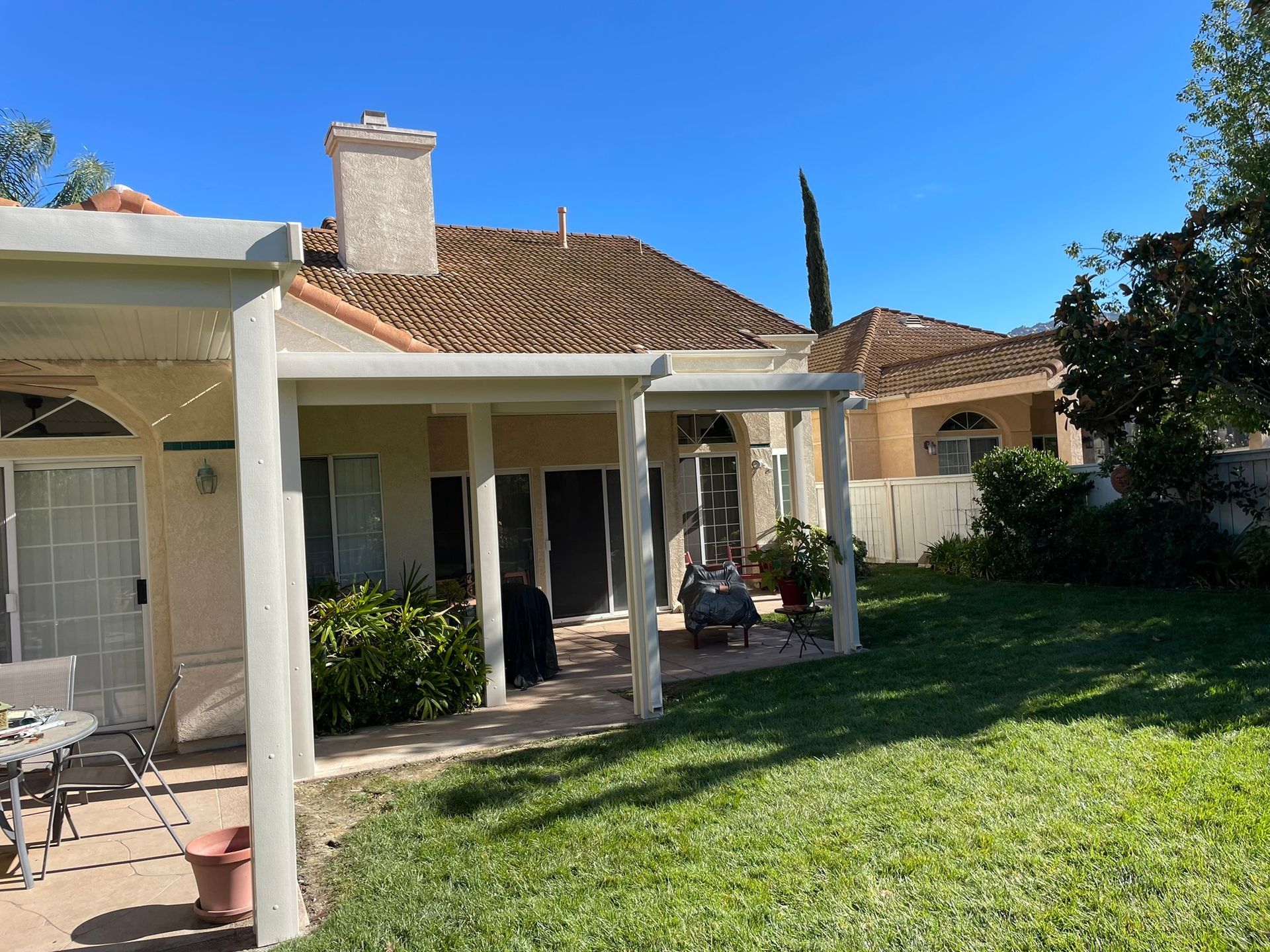 A house with a patio, green lawn, and blue sky.