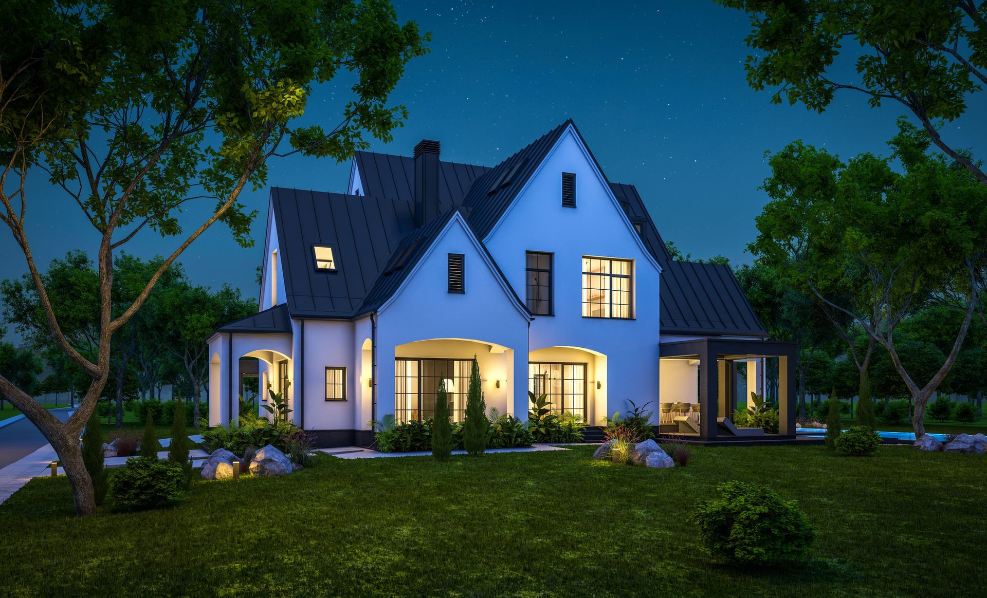 A large white house with a black roof is lit up at night.