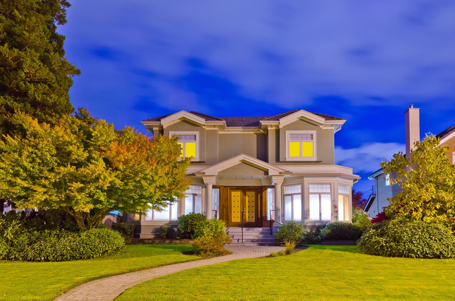 A large house with a path leading to it is lit up at night.