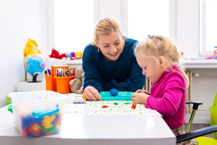 A woman is playing with a little girl at a table.