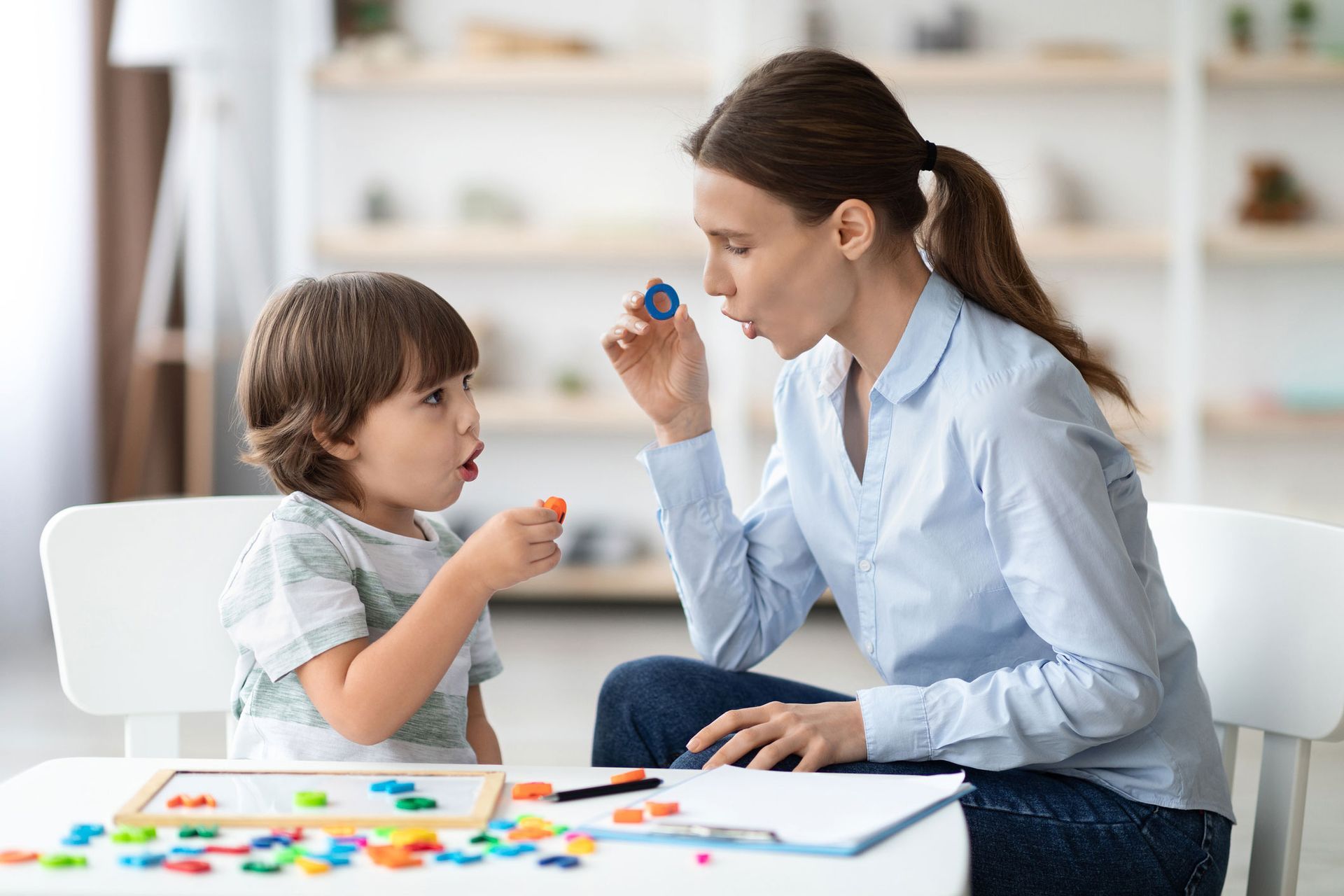A woman is sitting at a table playing with a child.