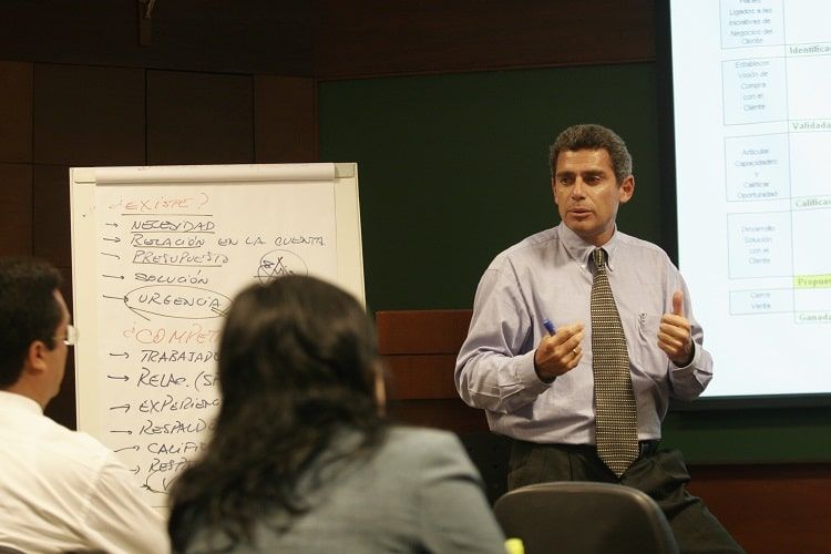 Un hombre con corbata está dando una presentación a un grupo de personas.