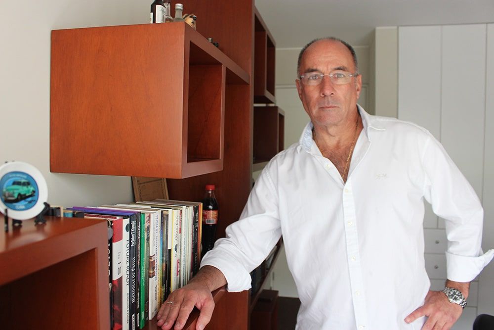 Un hombre con una camisa blanca está apoyado en una estantería.