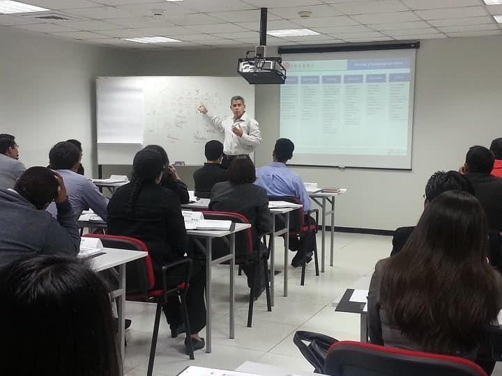 Un hombre está dando una presentación a un grupo de personas en un aula.