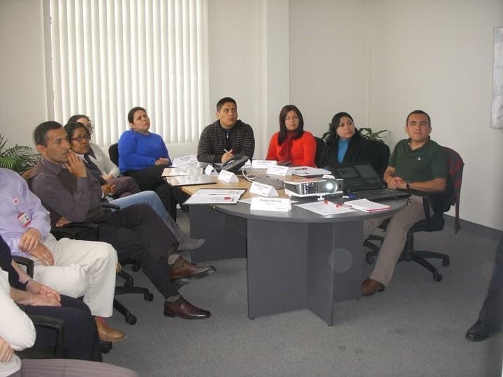 Un grupo de personas se sientan alrededor de una mesa en una sala de reuniones.