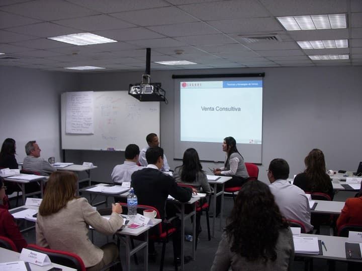 Un grupo de personas está sentado en un aula viendo una presentación.