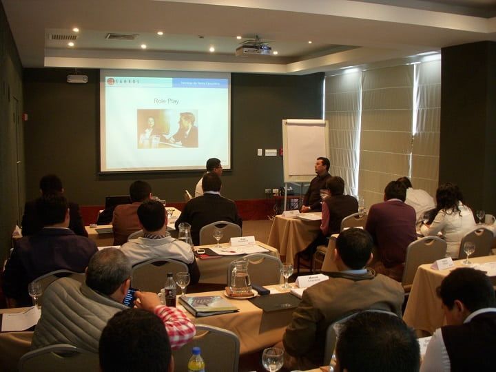 Un grupo de personas está sentado en una sala de conferencias viendo una presentación.
