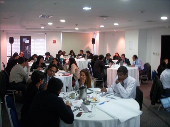 Un grupo de personas están sentadas en mesas en una habitación.