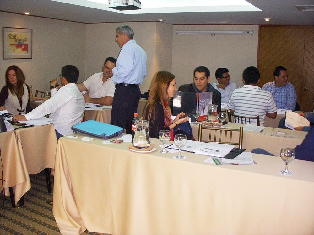 Un grupo de personas están sentadas en mesas en una sala de conferencias.