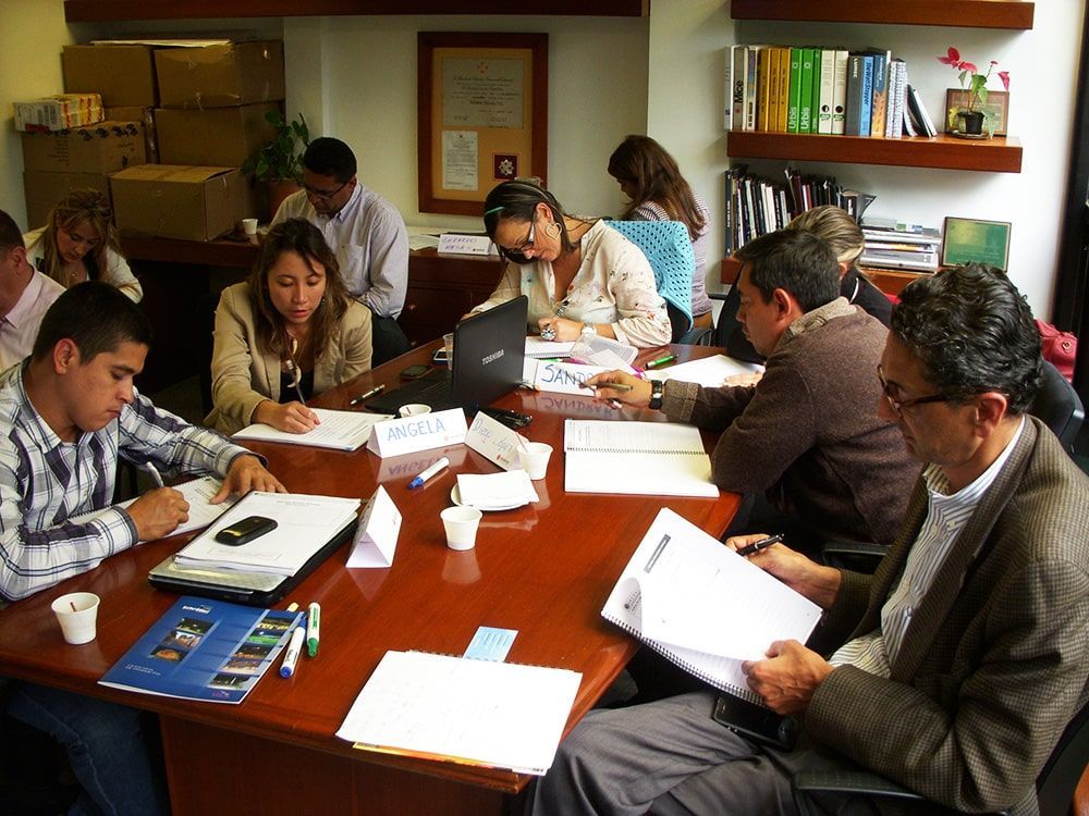 Un grupo de personas están sentadas alrededor de una mesa con papeles encima.