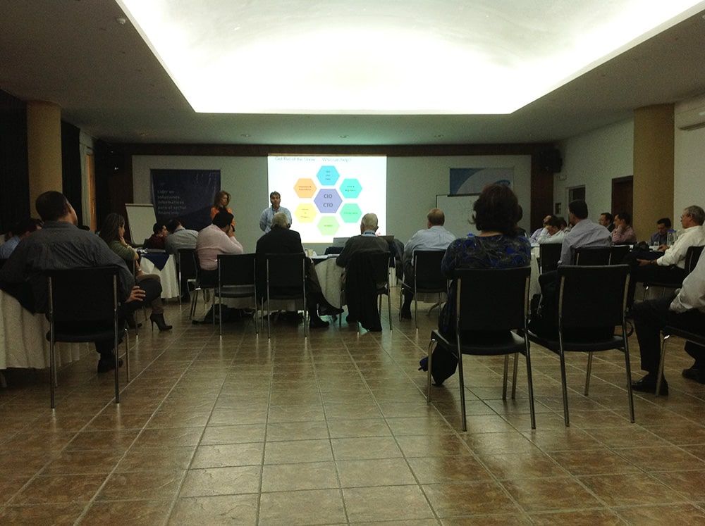 Un grupo de personas están sentadas en sillas frente a una pantalla de proyector.