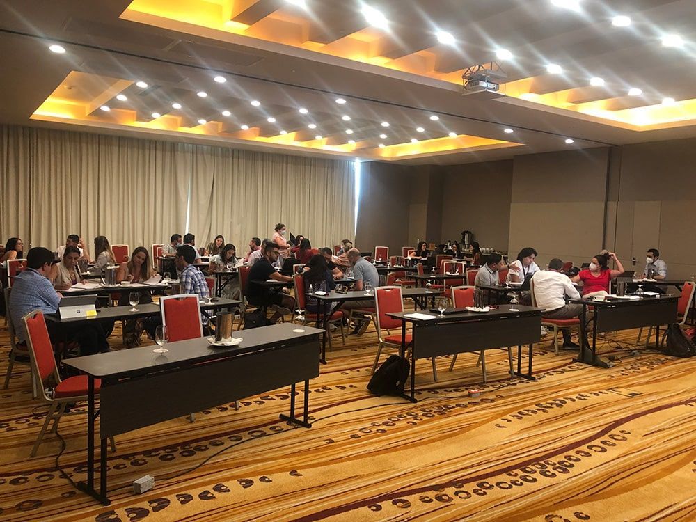 Un grupo de personas están sentadas en mesas en una sala grande.